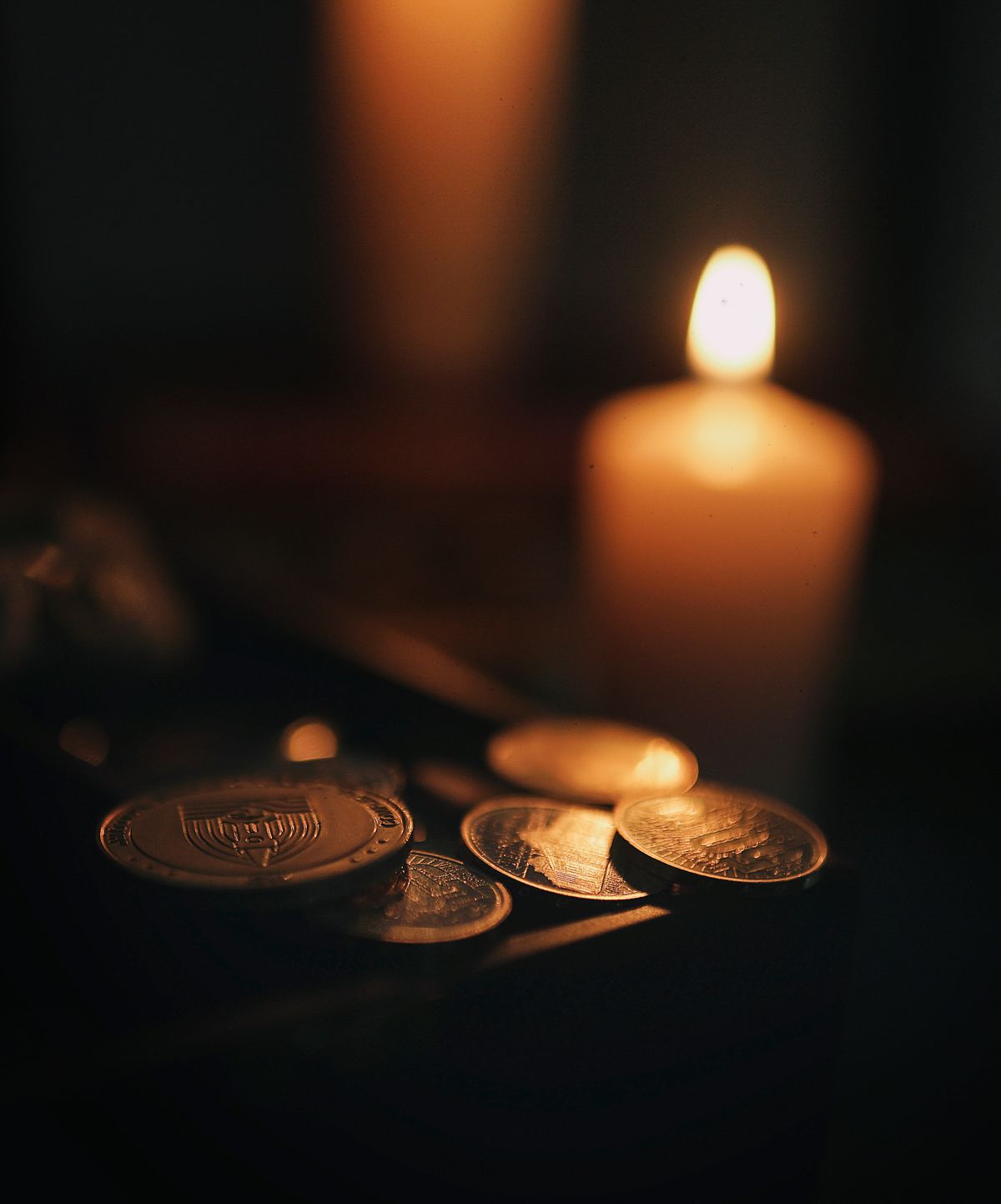 Monedas antiguas junto a vela encendida, ritual de abundancia