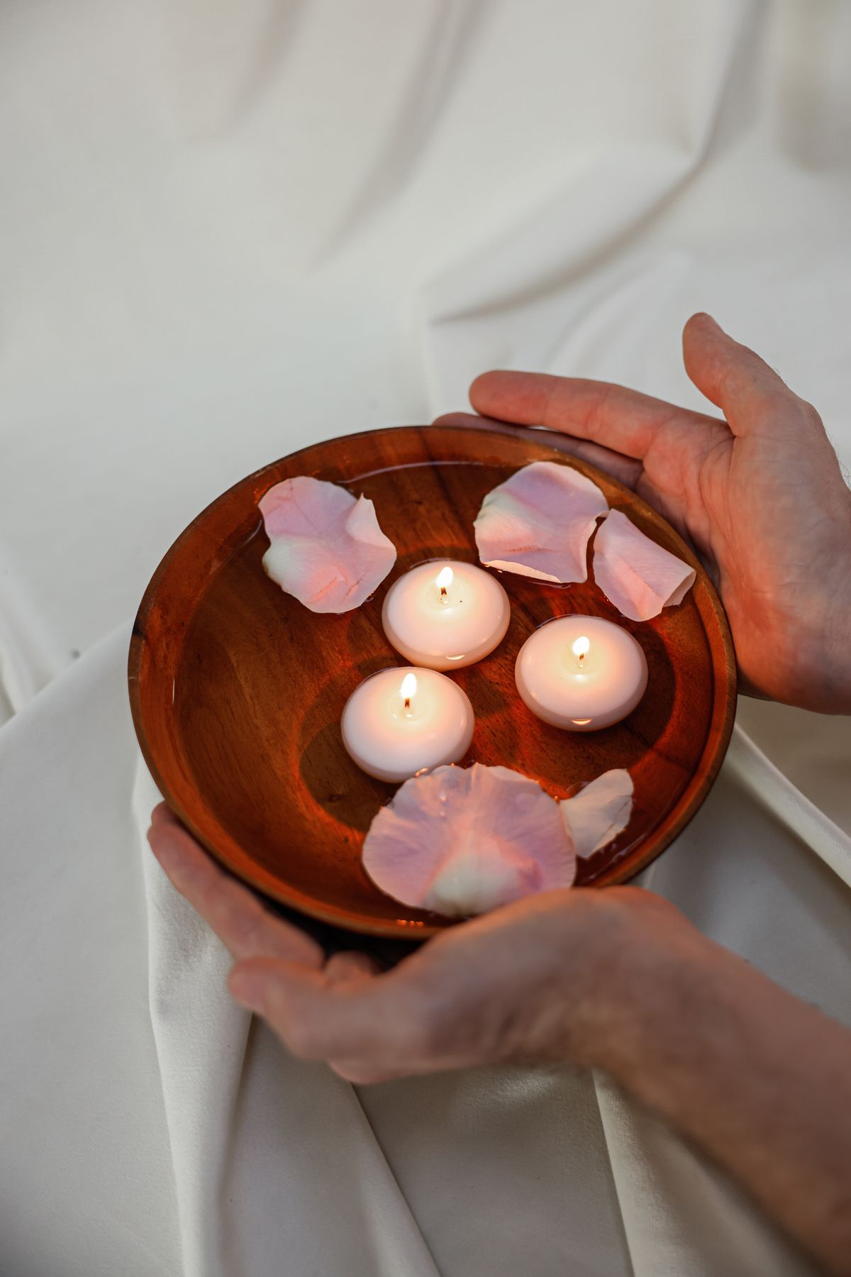 Velas flotantes con pétalos de rosa en cuenco de madera para ritual de amor