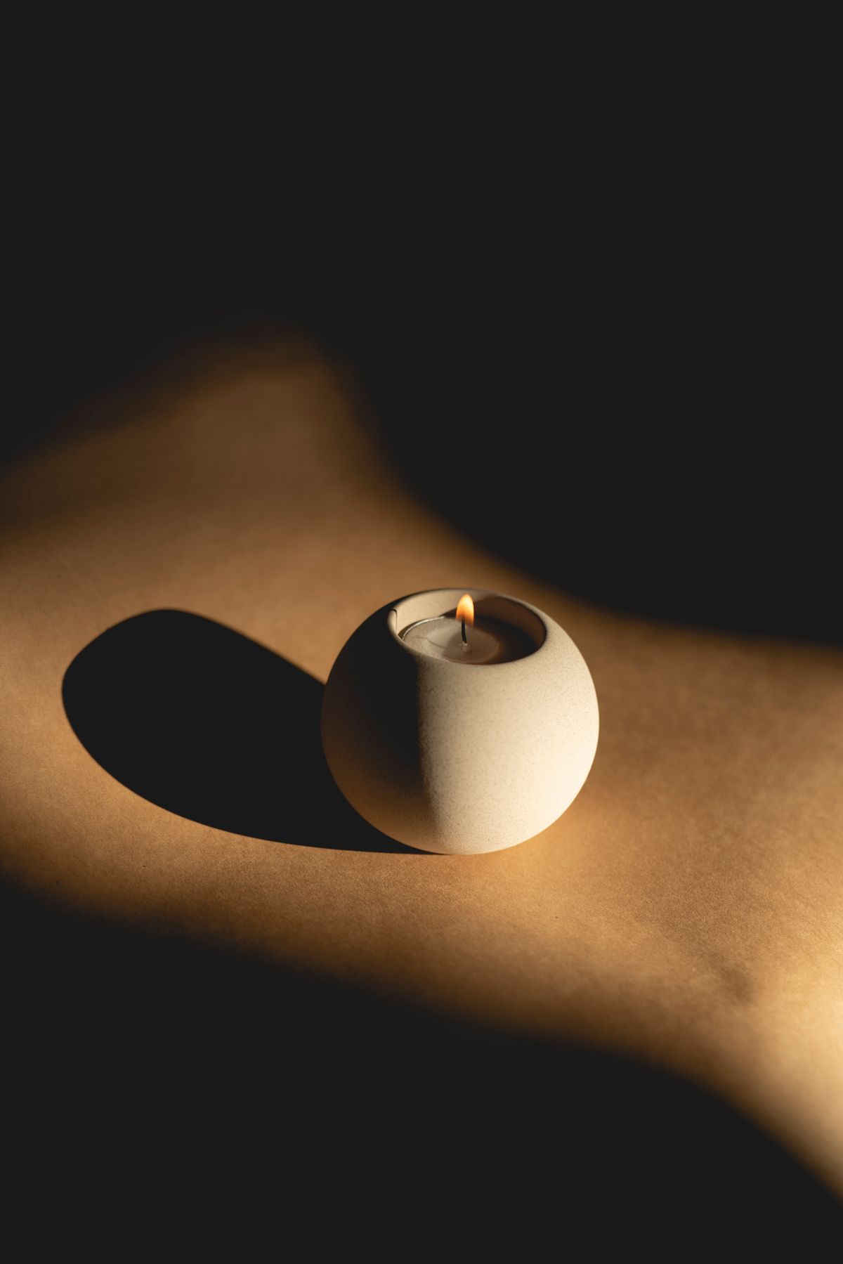 Vela en esfera de piedra entre luz y sombra, simbolizando el equinoccio